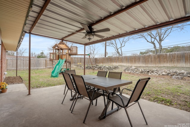 view of patio featuring outdoor dining area, a playground, and a fenced backyard