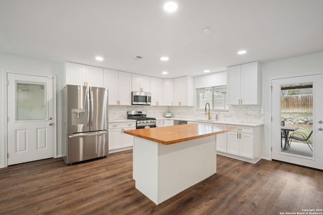 kitchen featuring dark wood-style floors, stainless steel appliances, white cabinetry, a sink, and wood counters