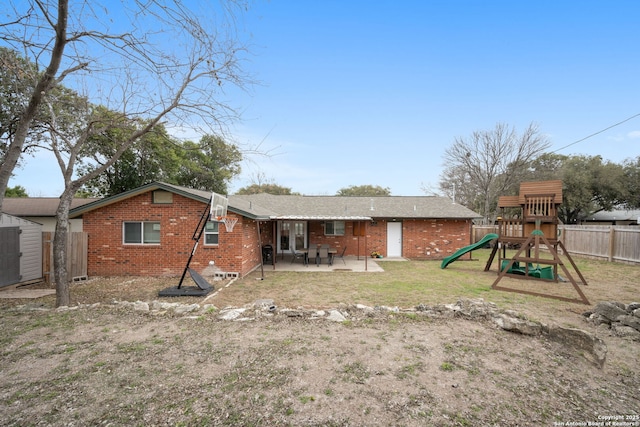 back of property with a patio, a playground, brick siding, fence, and a yard