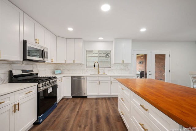 kitchen with dark wood-style flooring, stainless steel appliances, wooden counters, decorative backsplash, and a sink