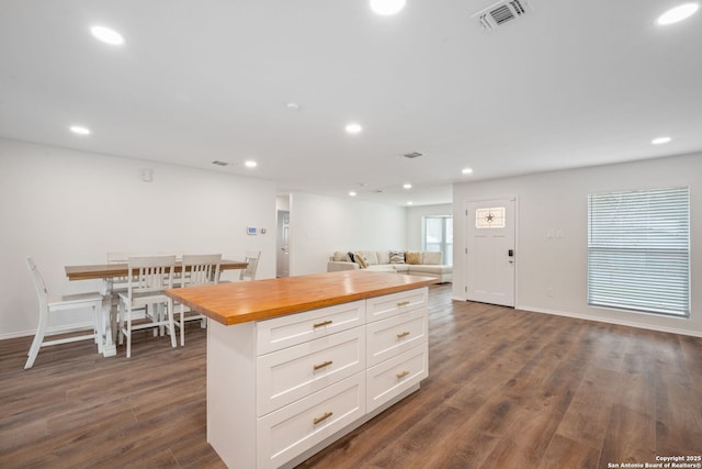 kitchen with dark wood-style flooring, visible vents, open floor plan, white cabinets, and wood counters