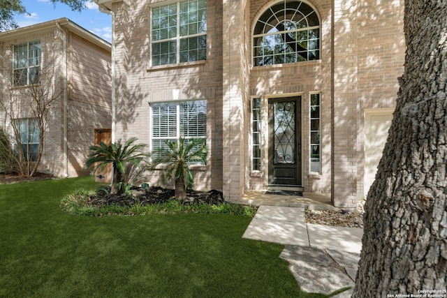 doorway to property with a yard and brick siding