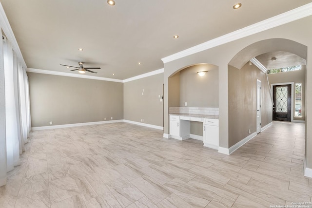 unfurnished living room with baseboards, arched walkways, a ceiling fan, built in desk, and recessed lighting