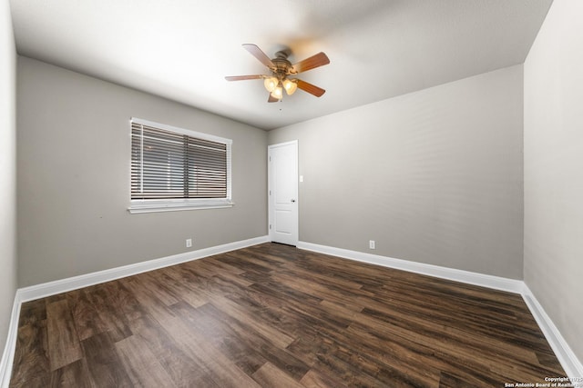 spare room featuring dark wood-style floors, ceiling fan, and baseboards