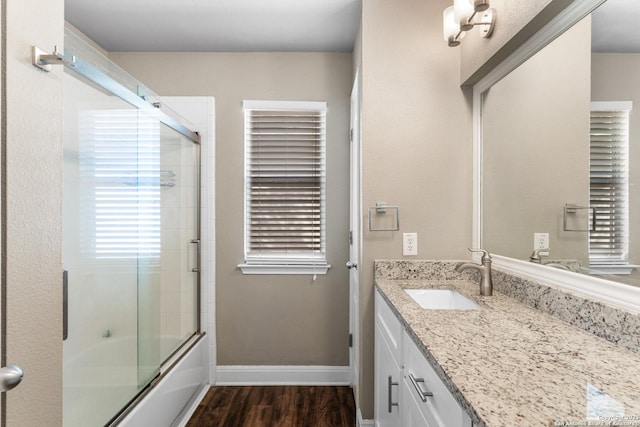 bathroom with combined bath / shower with glass door, vanity, baseboards, and wood finished floors