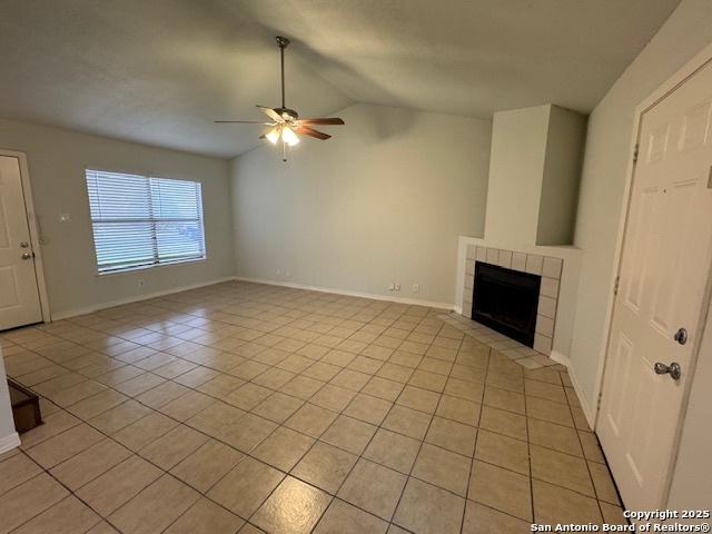 unfurnished living room with lofted ceiling, light tile patterned flooring, a tile fireplace, a ceiling fan, and baseboards