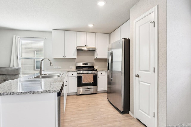 kitchen with stainless steel appliances, a sink, white cabinets, and under cabinet range hood