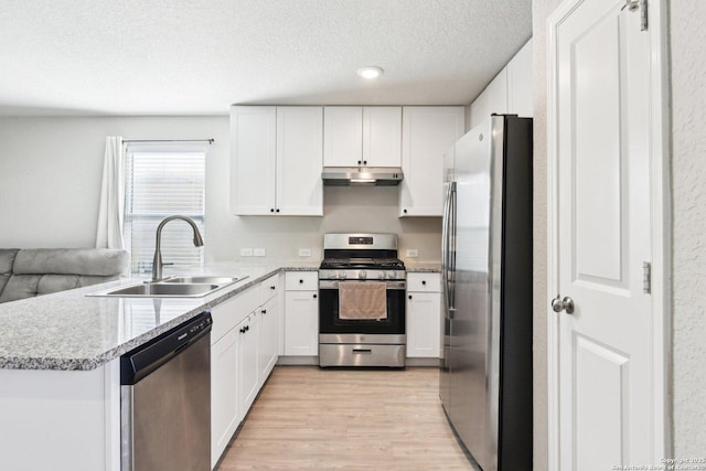 kitchen featuring appliances with stainless steel finishes, light wood-type flooring, under cabinet range hood, white cabinetry, and a sink