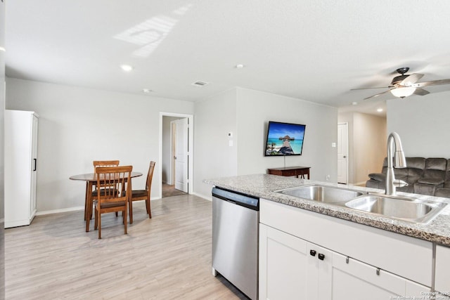 kitchen featuring a sink, a ceiling fan, white cabinets, stainless steel dishwasher, and light wood-type flooring