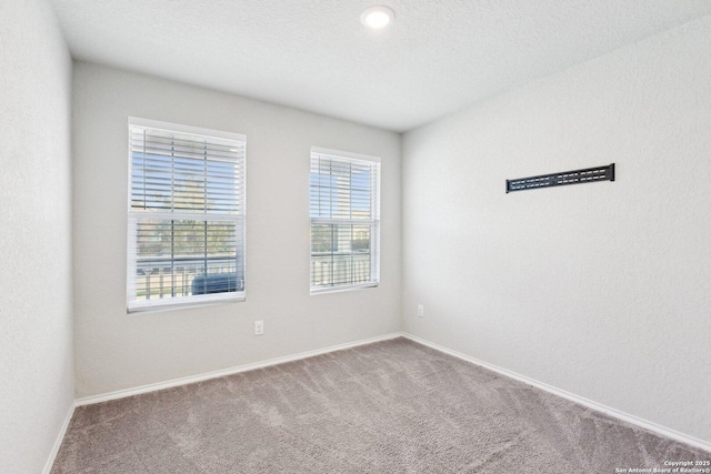 carpeted spare room featuring baseboards and a textured ceiling