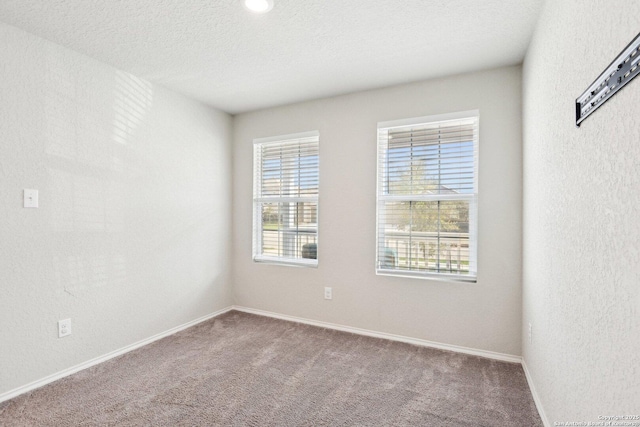 unfurnished room featuring carpet floors, baseboards, a textured ceiling, and a textured wall