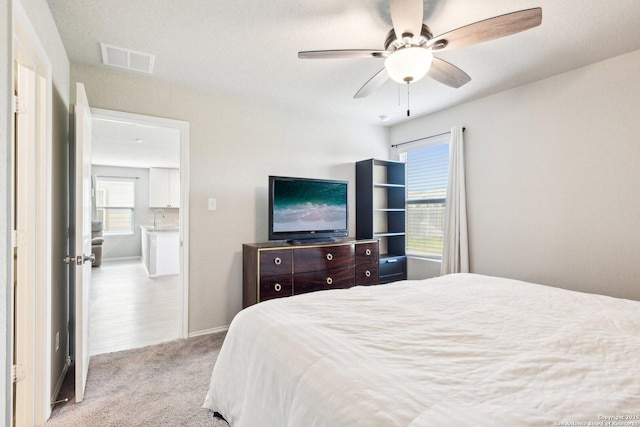 bedroom featuring carpet flooring, a sink, baseboards, visible vents, and a ceiling fan