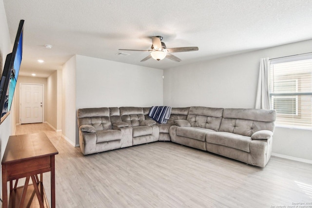 living room featuring light wood-type flooring, ceiling fan, baseboards, and a textured ceiling