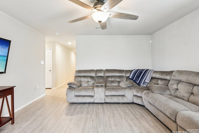 living room featuring ceiling fan, visible vents, baseboards, and wood finished floors