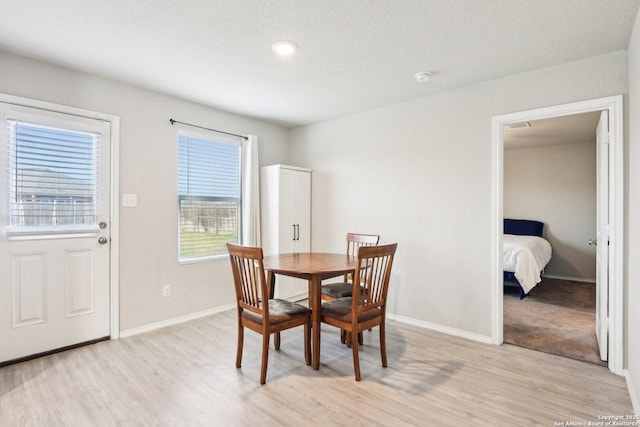 dining space with light wood-type flooring and baseboards