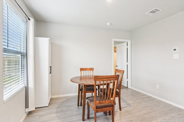 dining space featuring baseboards, visible vents, and light wood finished floors