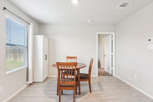 dining room featuring light wood finished floors, baseboards, and visible vents