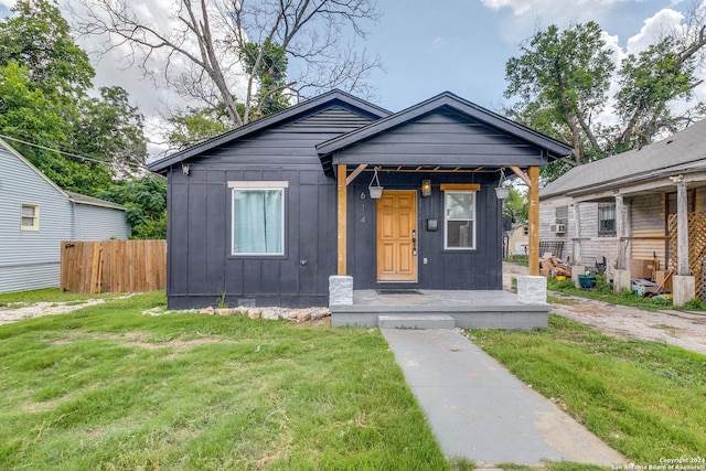 view of front of home with board and batten siding, a front yard, and fence