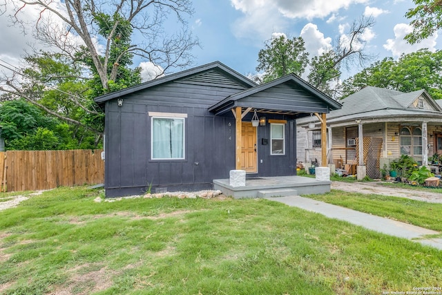 bungalow-style house with fence, board and batten siding, and a front yard