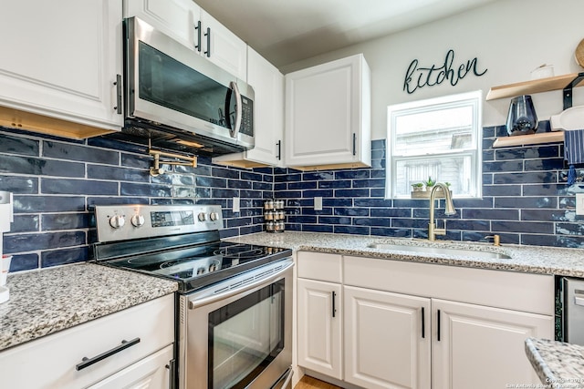 kitchen featuring white cabinets, decorative backsplash, stainless steel appliances, and a sink