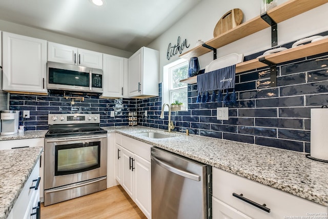 kitchen with stainless steel appliances, white cabinets, a sink, and open shelves