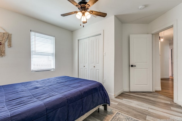 bedroom featuring a ceiling fan, light wood-style flooring, baseboards, and a closet