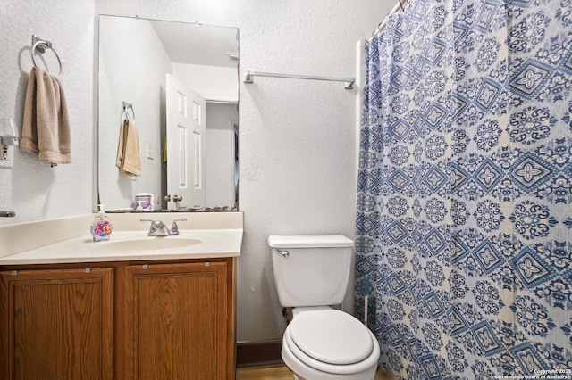 full bath featuring toilet, a textured wall, a shower with curtain, and vanity