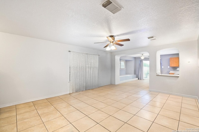 unfurnished room with arched walkways, a textured ceiling, visible vents, and a ceiling fan