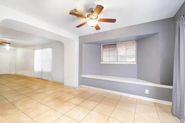 unfurnished room with a ceiling fan, baseboards, and light tile patterned floors