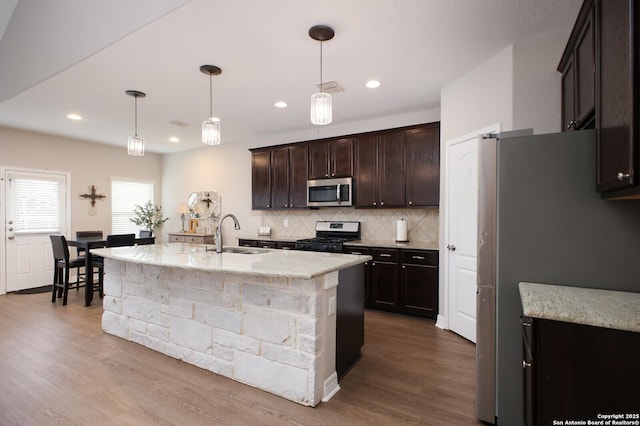 kitchen with stainless steel appliances, tasteful backsplash, visible vents, a sink, and wood finished floors