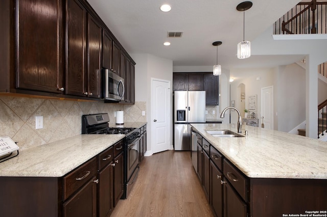 kitchen featuring dark brown cabinetry, stainless steel appliances, a sink, and light wood finished floors