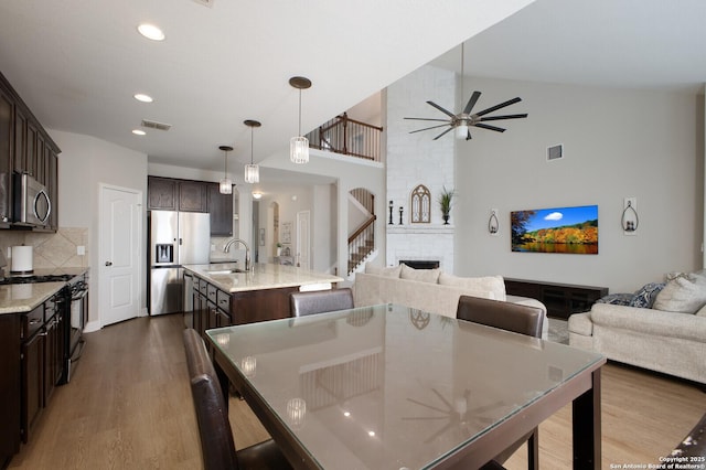 dining space featuring a ceiling fan, a fireplace, visible vents, and dark wood-style flooring