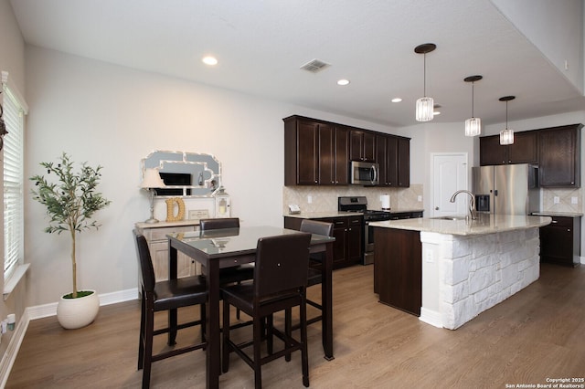 kitchen with appliances with stainless steel finishes, visible vents, dark brown cabinetry, and light wood-style flooring