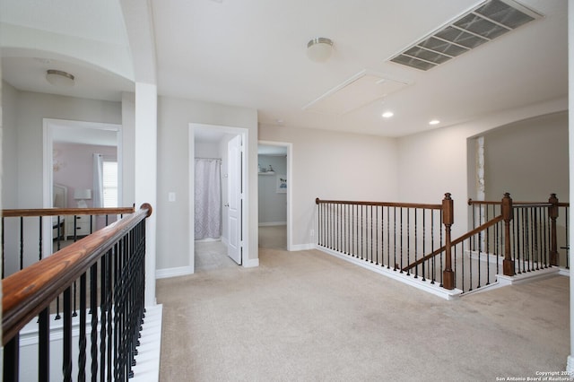 hall with attic access, baseboards, visible vents, carpet flooring, and an upstairs landing