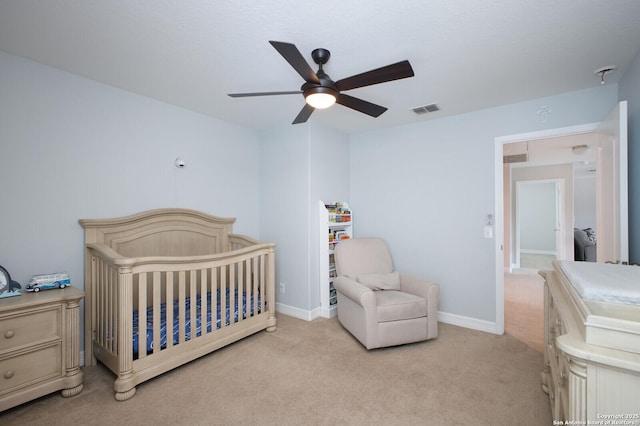 bedroom featuring light carpet, a nursery area, baseboards, and visible vents