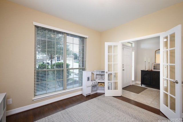 living area with baseboards, wood finished floors, and french doors