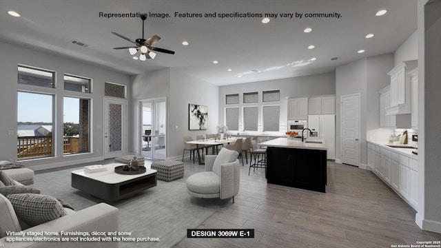 living room featuring visible vents, a ceiling fan, a high ceiling, light wood-type flooring, and recessed lighting