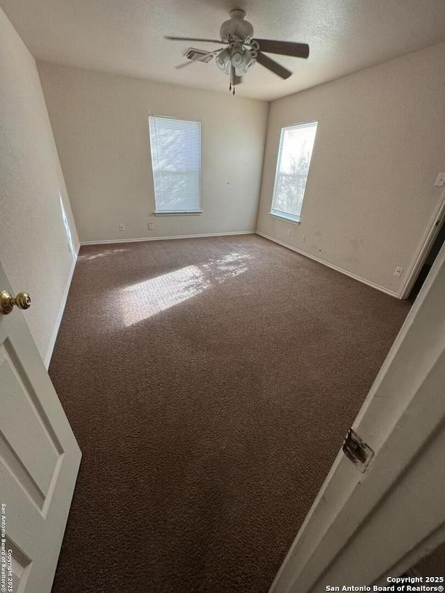 unfurnished room with carpet, visible vents, ceiling fan, a textured ceiling, and baseboards