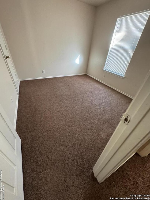 carpeted spare room with baseboards