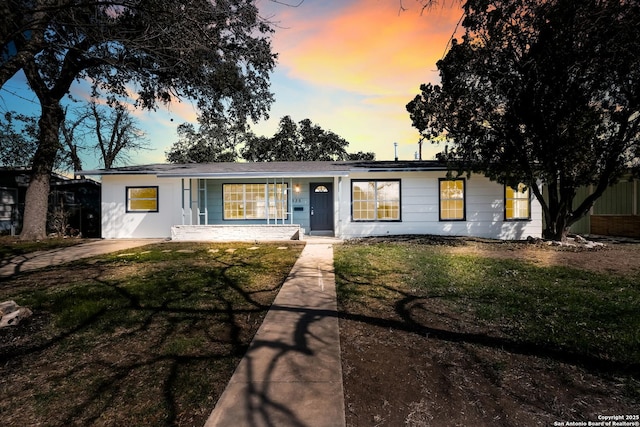 ranch-style home featuring a porch and a lawn