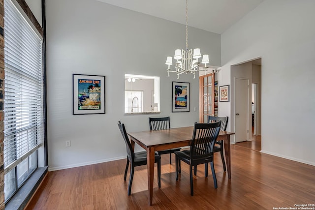 dining area featuring a high ceiling, baseboards, and wood finished floors