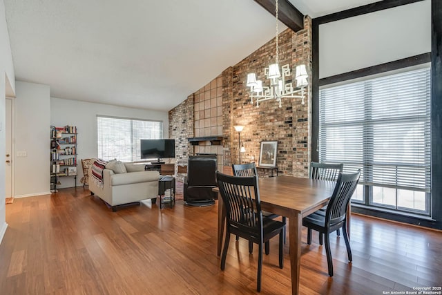 dining room with high vaulted ceiling, brick wall, wood finished floors, a brick fireplace, and beamed ceiling