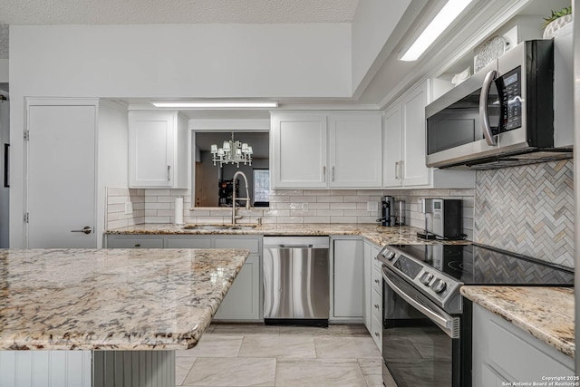 kitchen featuring light stone countertops, stainless steel appliances, a sink, white cabinets, and decorative backsplash