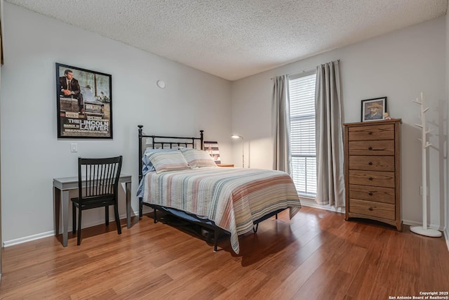 bedroom featuring light wood-style floors, baseboards, and a textured ceiling