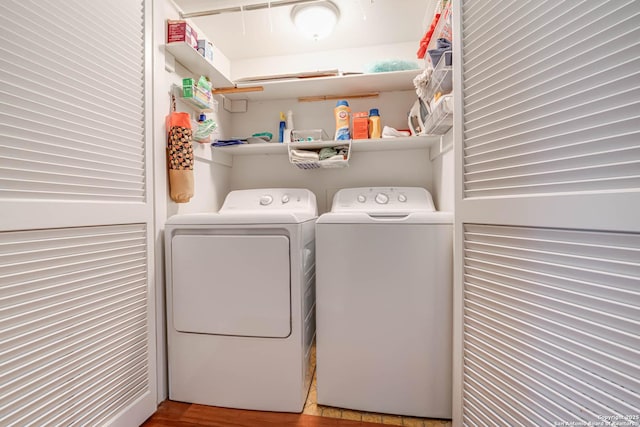 clothes washing area featuring washing machine and dryer, laundry area, and wood finished floors