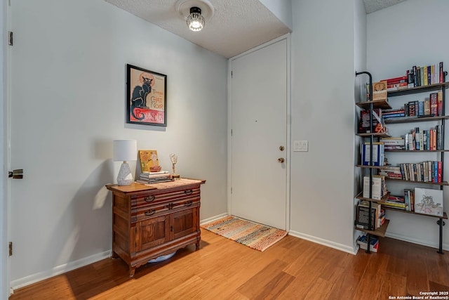 entryway featuring a textured ceiling, baseboards, and wood finished floors