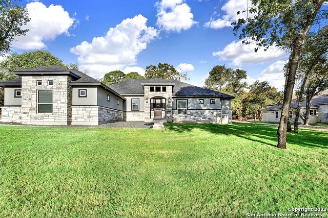 view of front of property featuring stone siding, stucco siding, and a front yard