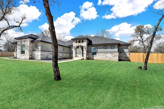 prairie-style home with fence, stone siding, stucco siding, a chimney, and a front yard