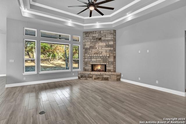 unfurnished living room with a raised ceiling, a fireplace, crown molding, and wood finished floors