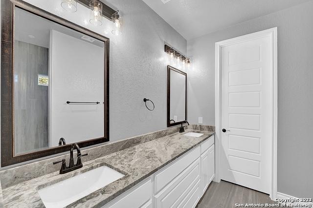 bathroom featuring wood finished floors, a sink, and double vanity